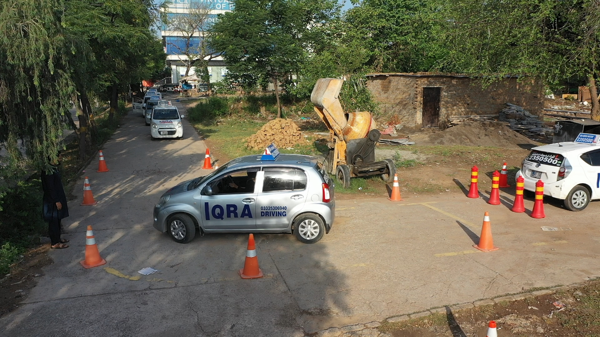 "Iqra Driving training car practicing a driving test on a cone-marked course at a driving school in Pakistan."